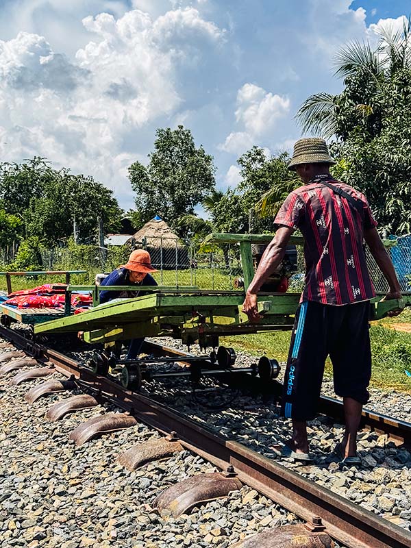 Two Cambodians lifting the bamboo train onto the tracks in Battambang