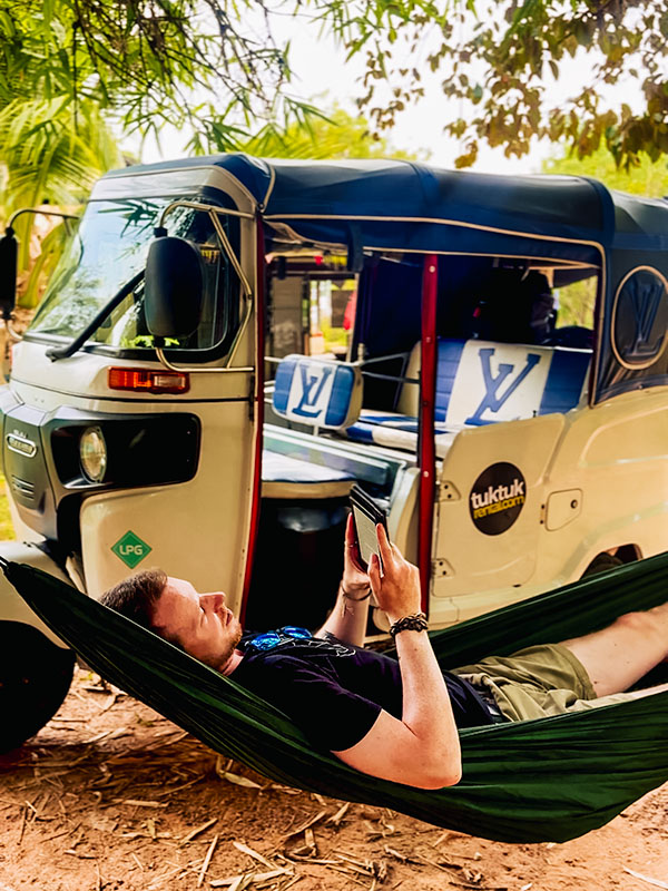 Matt reading book in a hammock in front of white tuktuk