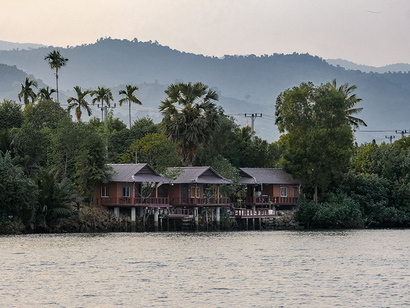 Riverside hotel lodges set against the mountains along the banks of Kampot River, Cambodia