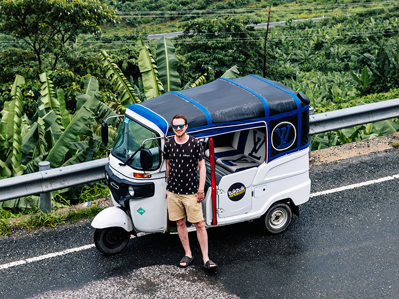 Matt standing in front of a white tuktuk (with TukTuk Rental branding) on the Phnom 1500, Cambodia
